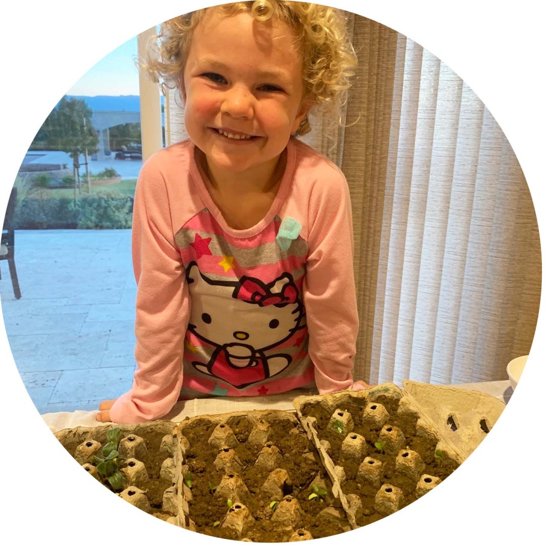 A child standing over egg cartons filled with soil