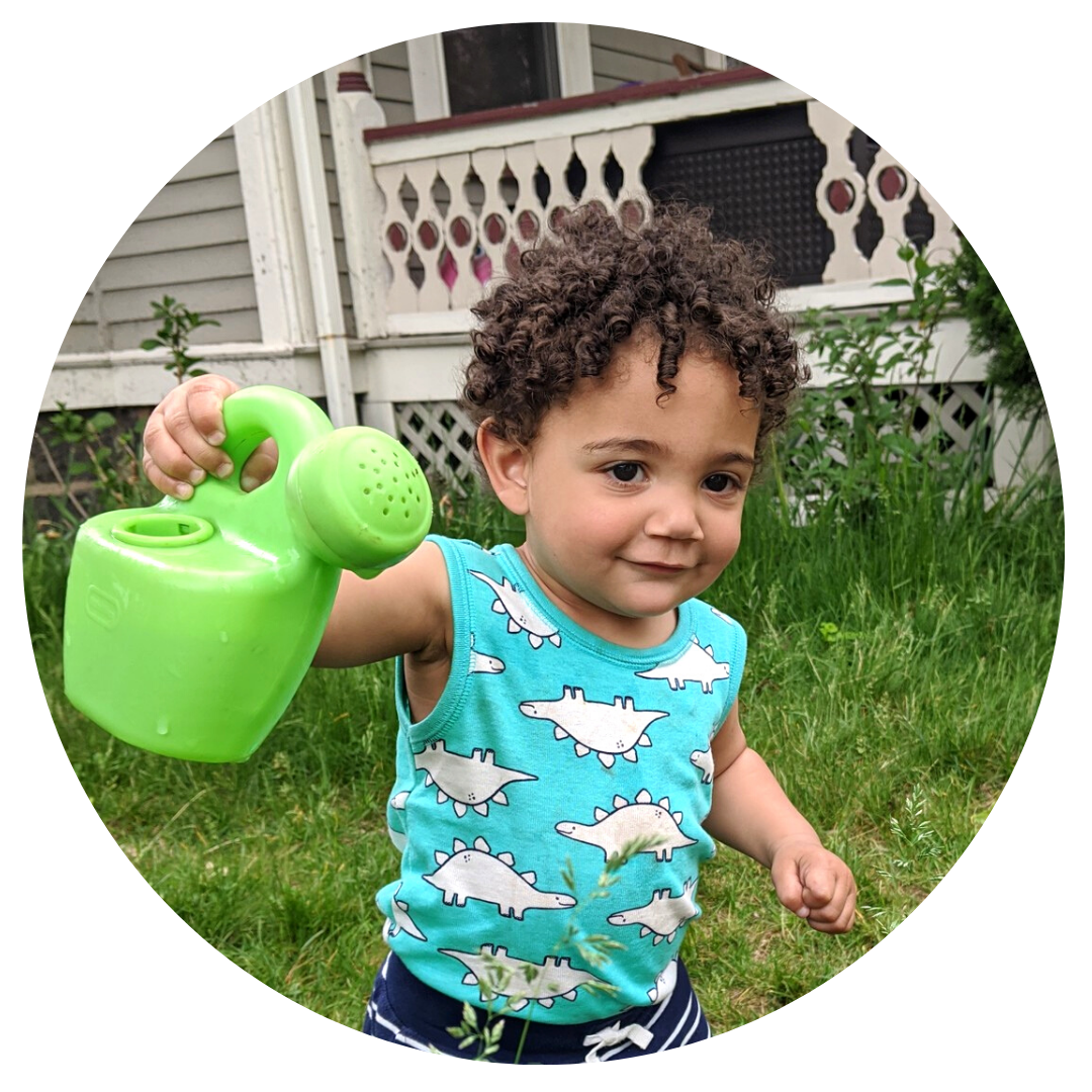 A young child holding a green plastic watering can